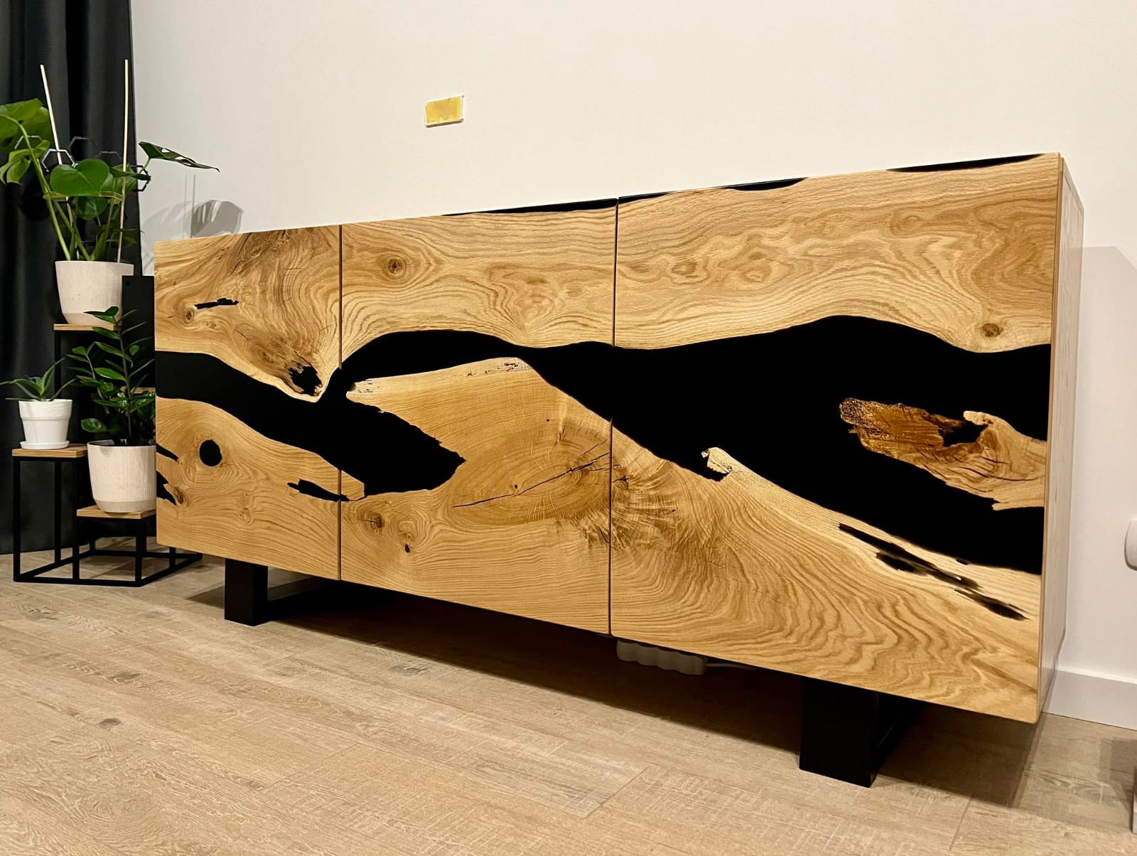 Prezentacja nowoczesnej komody z litego drewna i czarnej żywicy epoksydowej, jako przykładu designerskiego mebla w aranżacji wnętrz.