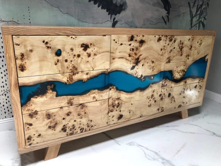 Prezentacja nowoczesnej komody wykonanej z drewna o charakterystycznych naturalnych wybarwieniach (tzw. burl) i wypełnionej turkusową żywicą epoksydową, jako unikatowego elementu wyposażenia wnętrz.
