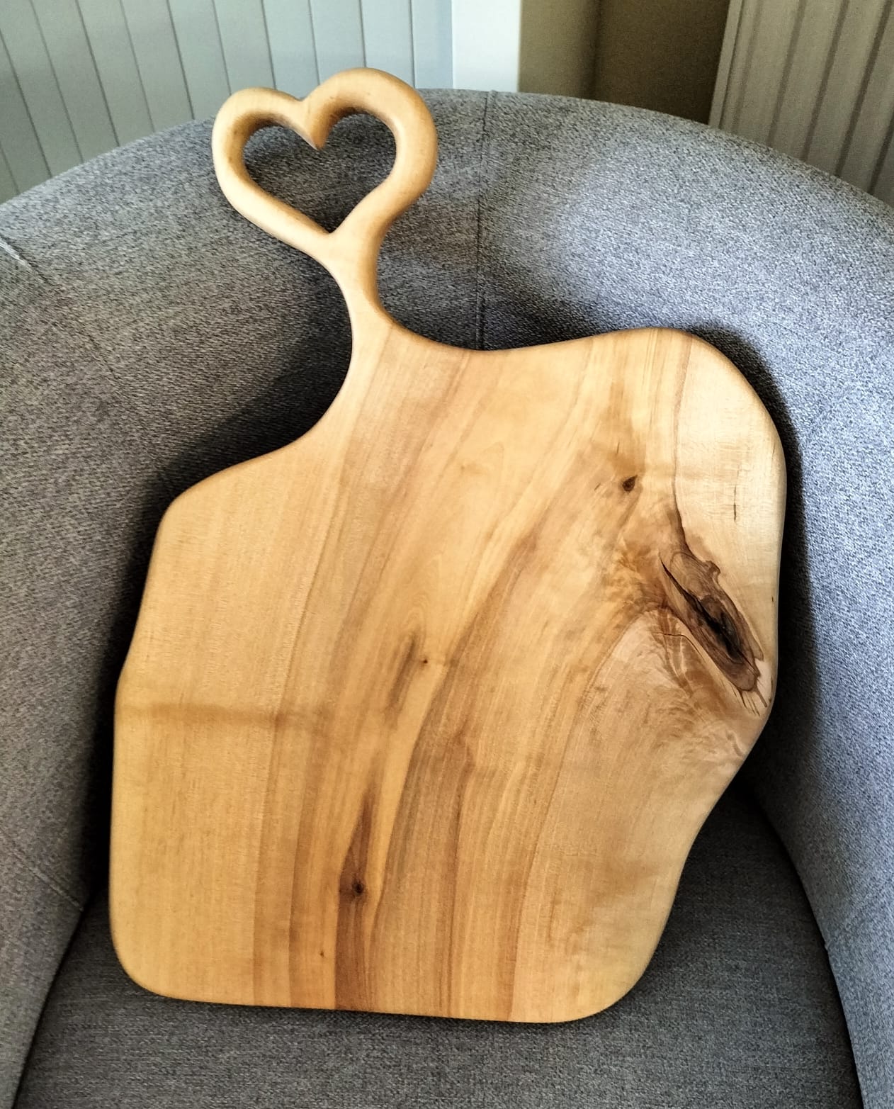 Prezentacja ręcznie wykonanej, drewnianej deski do krojenia lub serwowania, z uchwytem w kształcie serca.