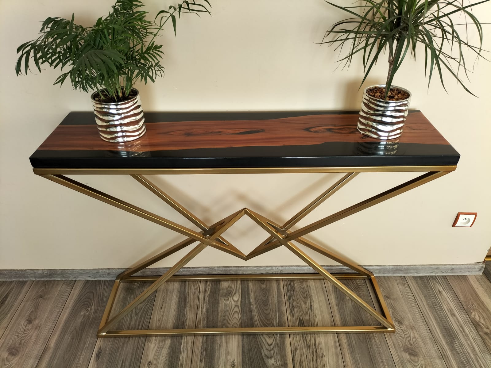 Prezentacja eleganckiej konsoli z drewna i żywicy epoksydowej, osadzonej na złotej, geometrycznej podstawie, jako elementu dekoracyjnego w aranżacji wnętrz